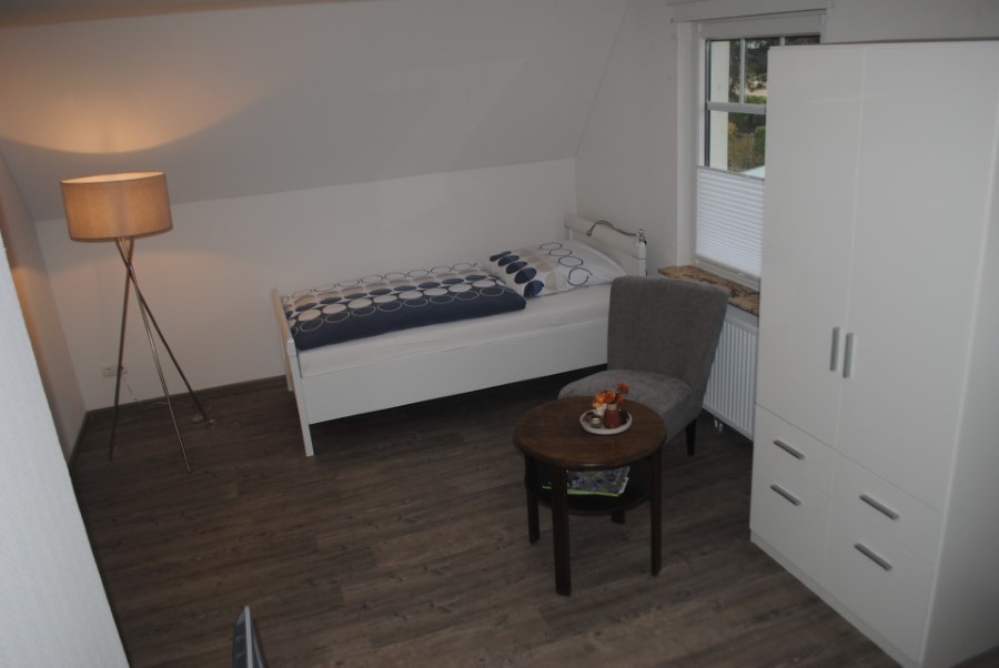 Schlafzimmer in Wohnung 3 mit Einzelbett, Sessel und Stehlampe